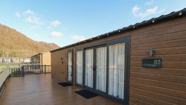 A wooden building with a balcony, a sliding glass door, and a sign reading "83 The Ridgeway". - The Ridgeway (New Quay)