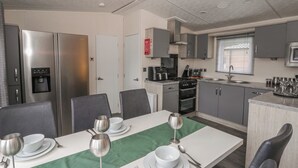 A compact kitchen with a refrigerator, stove, microwave, and sink. - The Ridgeway (New Quay)