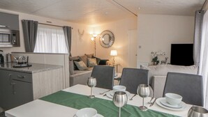 A dining area with a table set for four, a microwave, and a sofa in the background. - The Ridgeway (New Quay)