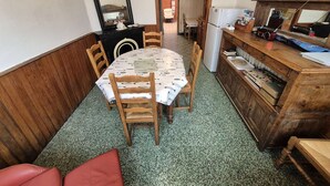Una cocina compacta con una mesa, sillas, un armario de madera y un espejo.