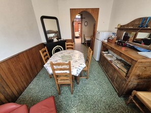 Une cuisine de taille réduite comprenant une table à manger, des chaises, un meuble en bois et un miroir.