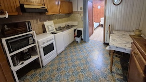 Una cocina compacta con armarios de madera, microondas, estufa y lavamanos.
