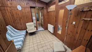 Una habitación de madera con sofá, una silla, una mesita y un radiador.