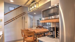 Una cucina compatta con un tavolo da pranzo in legno, sedie, un frigorifero in acciaio inossidabile e una macchina da caffè.