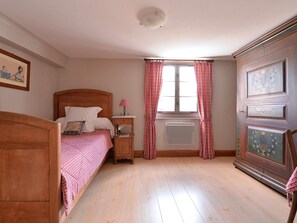 A bedroom with a wooden bed, a nightstand, a radiator, and a wardrobe.