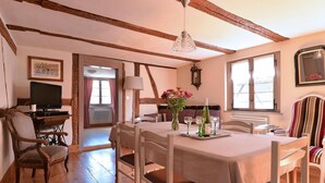 A dining area with a wooden table, chairs, and a television on a desk. - Charming Alsatian gîte near Colmar - 6 guests (Jebsheim)