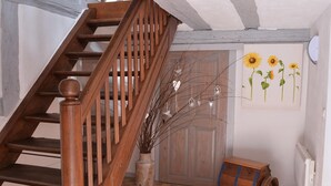 A wooden staircase with a checkered floor, a rustic wooden barrel, and a wall with sunflower artwork. - Charming Alsatian gîte near Colmar - 6 guests (Jebsheim)