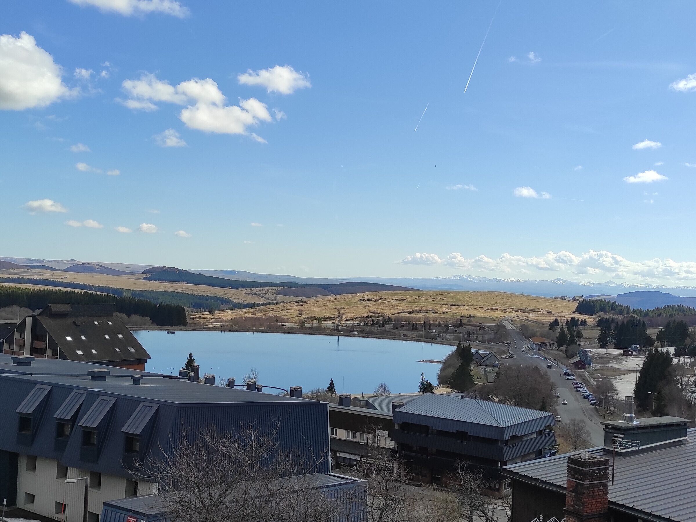 A lake with buildings in the foreground and mountains in the background.