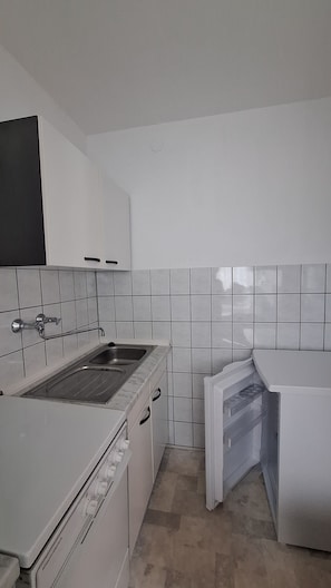 A small kitchen with white cabinets, a sink, and a stove.