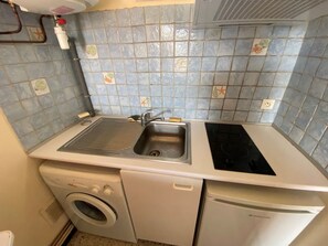 Una cocina compacta con lavaplatos, lavadora, estufa y pileta integrada.