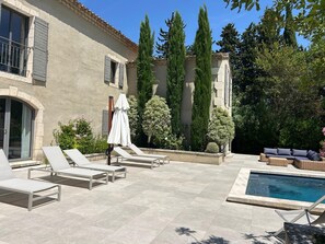 A poolside area with lounge chairs, a covered seating area, and a swimming pool. - Contemporary House with Pool in Maussane (Maussane-les-Alpilles)