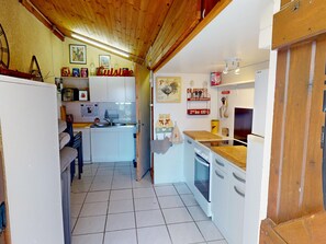A compact kitchen with white cabinets, a wooden countertop, and a tiled floor.