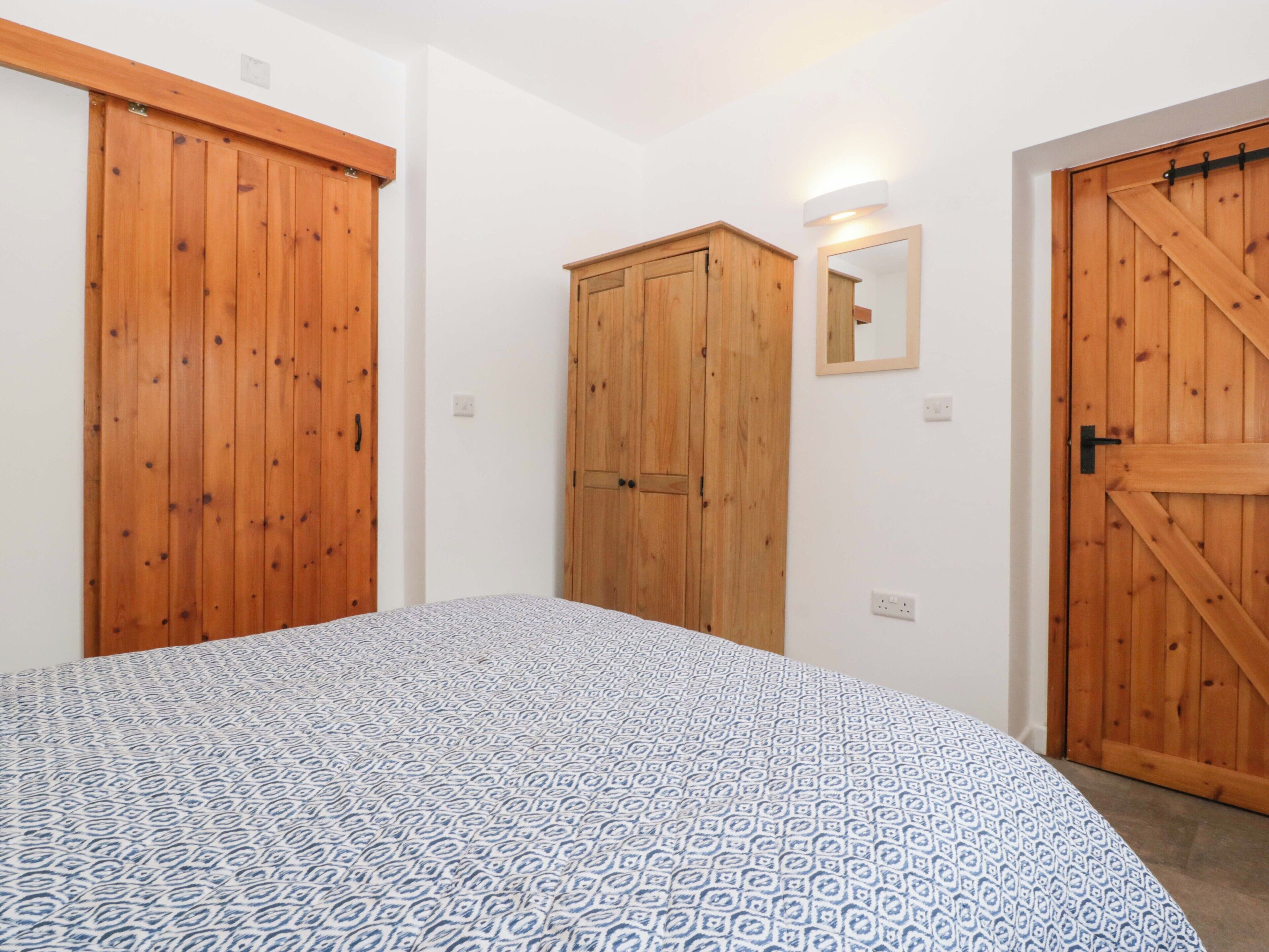 Une chambre à coucher avec un lit, des armoires en bois, un miroir et un luminaire.