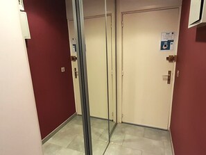A hallway with a glass partition, a door with a poster, and a red wall. - Air-Conditioned Studio with Balcony & Parking - Cap d'Agde (Cap d'Agde)