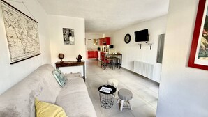 Un salon avec un canapé, une petite table ronde et, au fond, une cuisine.