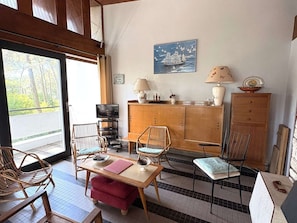 A room with a wooden cabinet, a television, wicker chairs, a table, and a painting of a sailboat. - Architect-designed villa, near beach - 9 guests (Lège-Cap-Ferret)