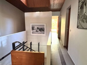 A hallway with a staircase, a framed photograph on the wall, and a door at the end. - Architect-designed villa, near beach - 9 guests (Lège-Cap-Ferret)