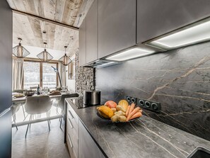Eine moderne Küche mit Marmorarbeitsplatte, Steinrückwand und großem Fenster.