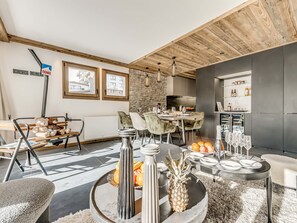 Ein modernes Wohnzimmer mit Essbereich, Küche und einer Steinwand.