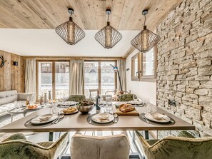 A dining area with a wooden table set for four, surrounded by stone walls and wooden beams. - Tignes, 3-Bedroom Chalet, 8 Guests, Wifi Included (Tignes)