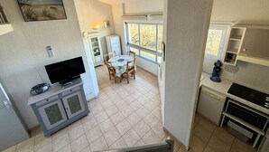 Uma cozinha compacta com área de refeições, TV e janela com vista para árvores.