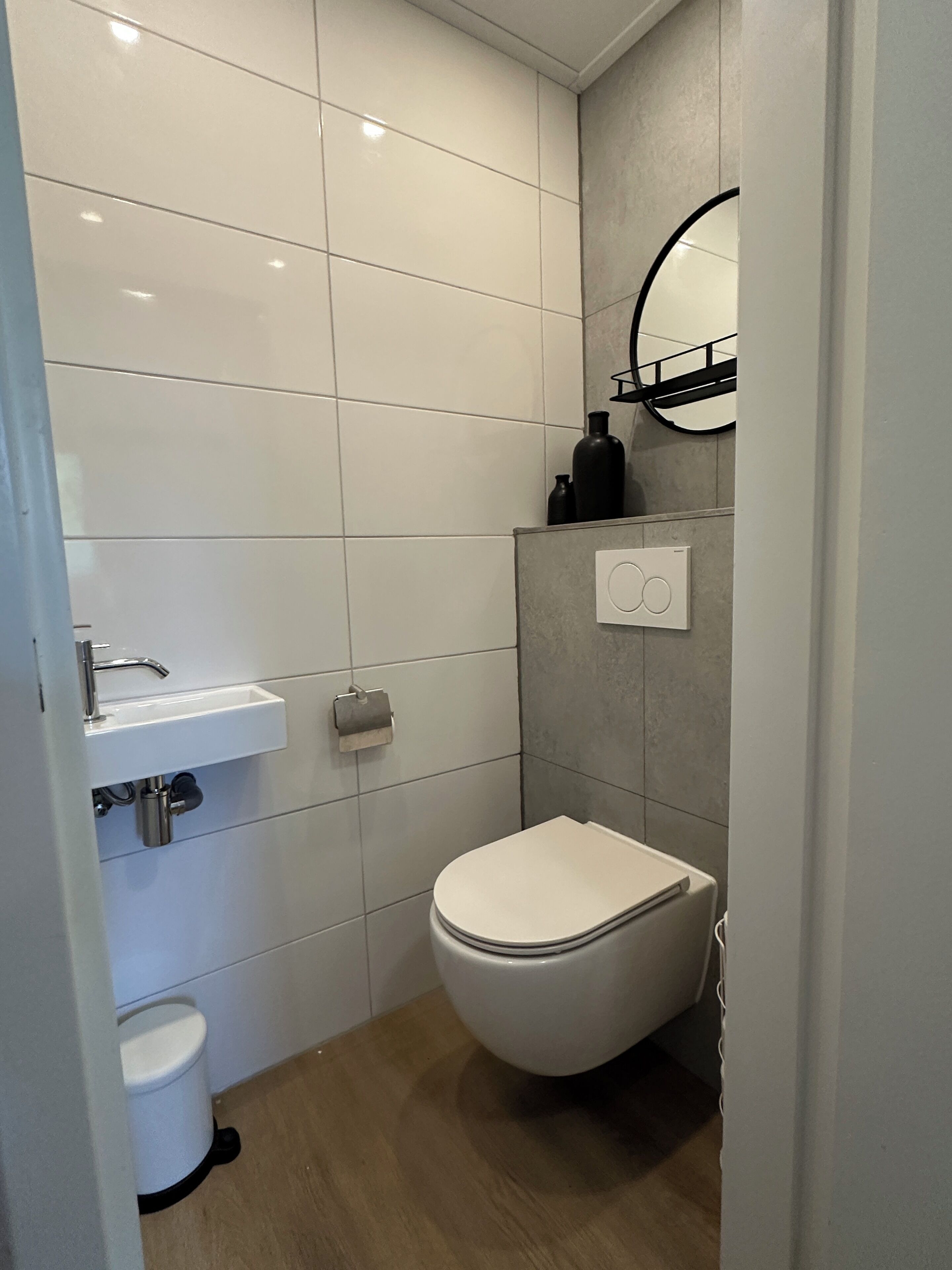 A modern bathroom with a white toilet, a sink, and a mirror.