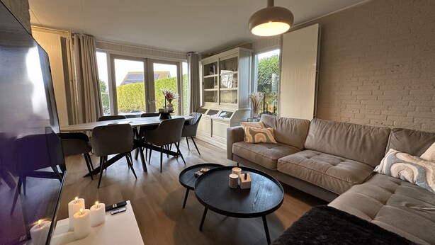 Ett modernt vardagsrum med en soffa, ett soffbord och en matplats.