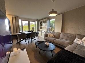 A modern living room with a sofa, coffee table, and dining area. - Hornzicht Vacation Home (Eanjum)