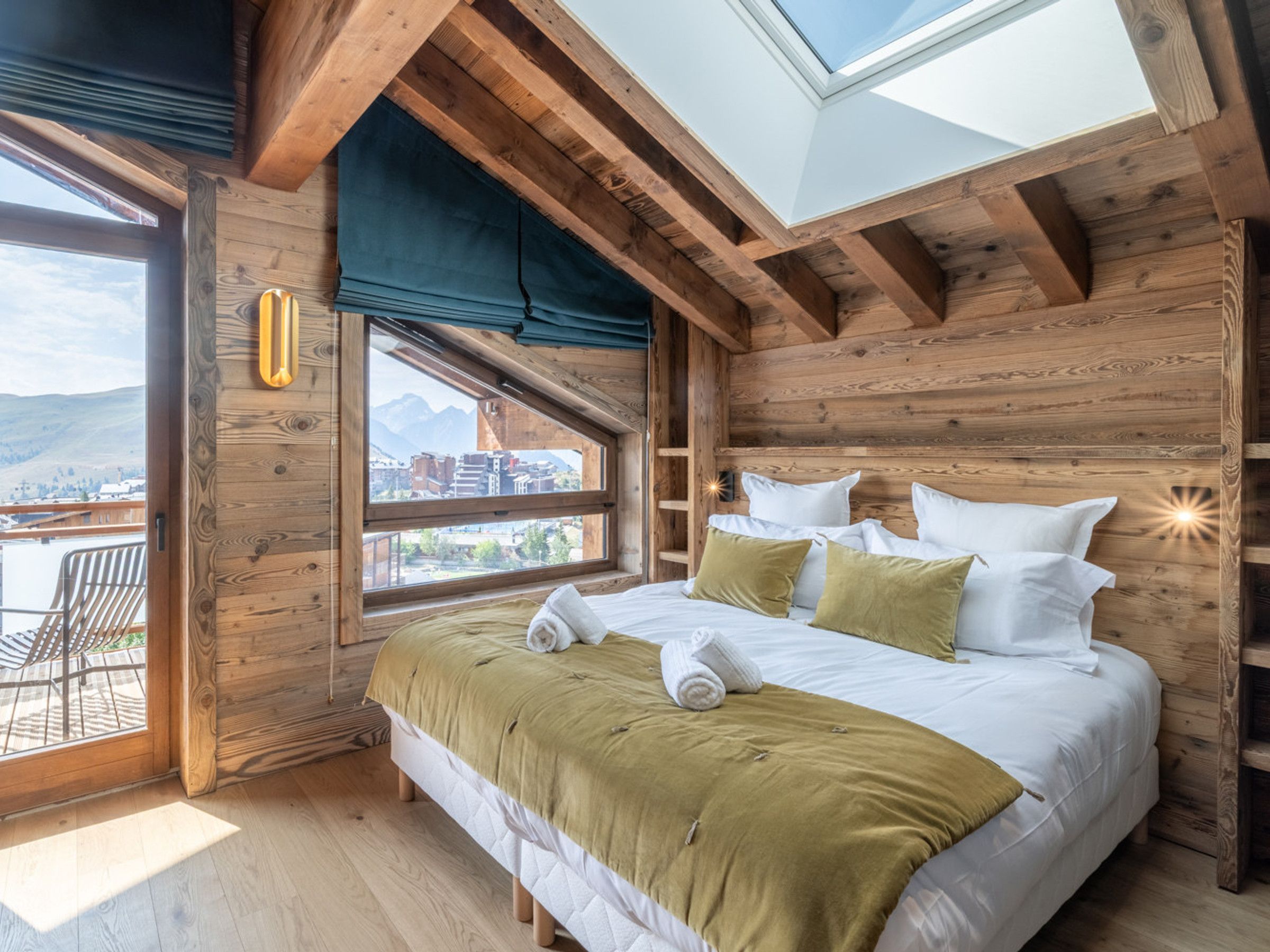 A wooden room with a bed, a window, and a view of a mountain.