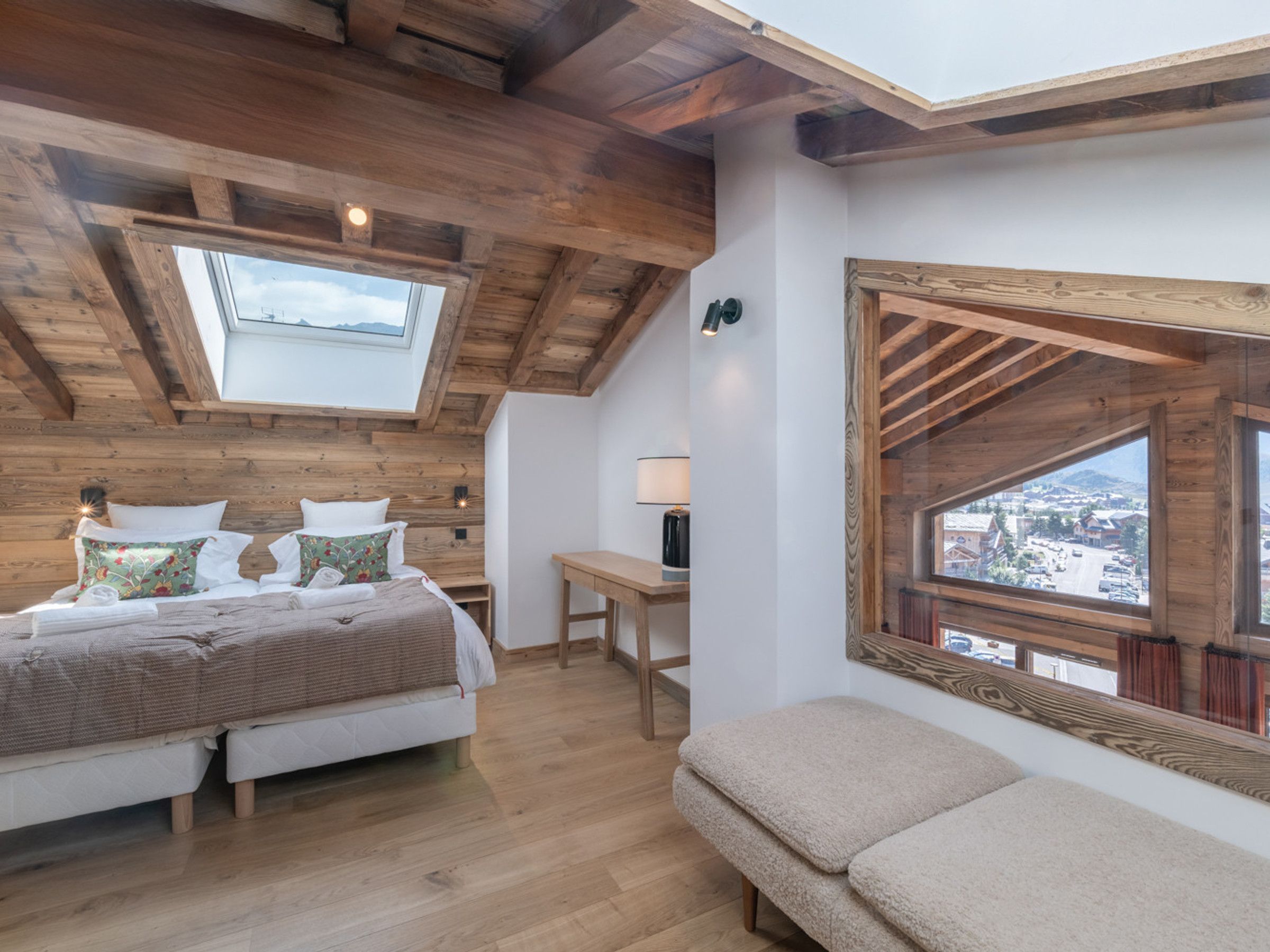 Une chambre avec une lucarne, un lit avec des oreillers, une table de chevet et une vue sur l’extérieur.
