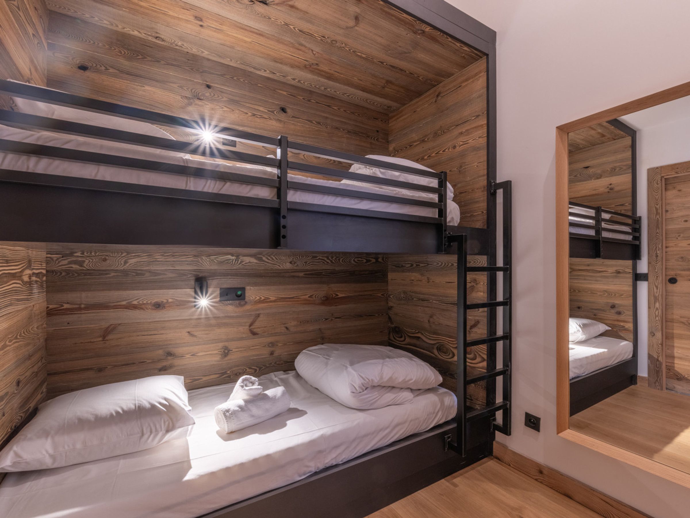 A bunk bed room with wooden paneling and a mirror on the wall.