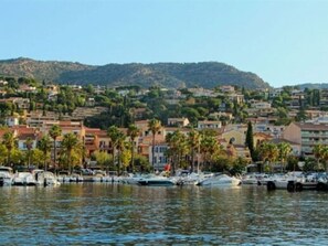 A marina with boats docked, surrounded by residential buildings and a hilly landscape. - Spacious Apt 4 ppl with pool near beach (Le Lavandou)