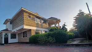 A two-story house with a balcony, a paved driveway, and a well-maintained garden. - Rhacky Homes Syokimau | Near JKIA 5 - 10 minutes' drive | Free WI-FI & Parking. (Machakos)