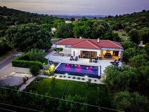 Ein modernes Haus mit Swimmingpool, umgeben von üppiger Vegetation und schöner Aussicht.