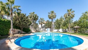 Une piscine entourée de palmiers et un bâtiment en arrière-plan.