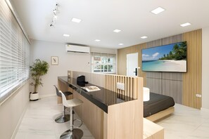 A modern hotel room with a kitchen area, a bed, and a large TV displaying a beach scene. - Bangkok's Most Beautiful Modern  Villa (Bangkok)