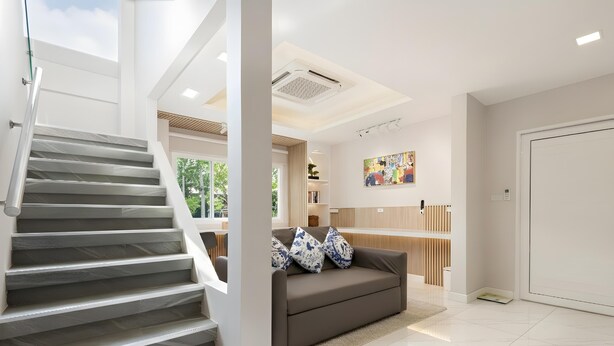 A modern interior with a staircase, a sofa with patterned cushions, and a kitchen area. - Bangkok's Most Beautiful Modern Villa (Bangkok)