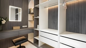 A modern bathroom with a vanity, a mirror with LED lighting, a bench, and built-in shelves. - Bangkok's Most Beautiful Modern Villa (Bangkok)