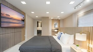 A modern bedroom with a large bed, a TV on the wall, and a bathroom in the background. - Bangkok's Most Beautiful Modern Villa (Bangkok)