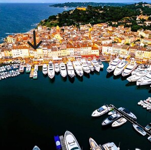 An aerial view of a coastal town with a marina filled with yachts and boats.