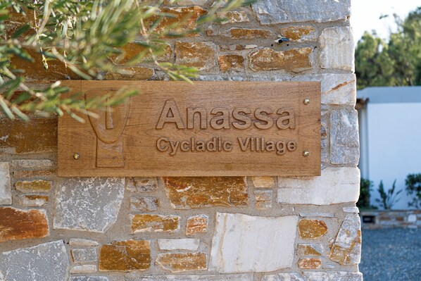 A wooden sign with the text "Anassa Cycladic Village" mounted on a stone wall. - Anassa Cycladic Village (Galissas)