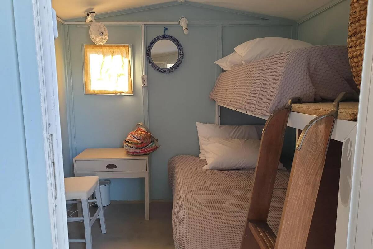 A compact room with bunk beds, a desk, and a small stool.