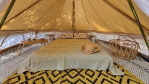 Uma tenda com uma cama, um chapéu e uma cesta.
