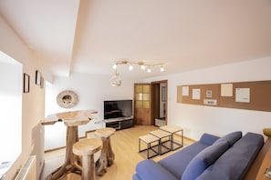 A modern living room with a wooden coffee table, a blue sofa, and a television.