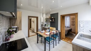 Une cuisine moderne avec un coin repas, des appareils électroménagers intégrés et une vue sur la chambre.