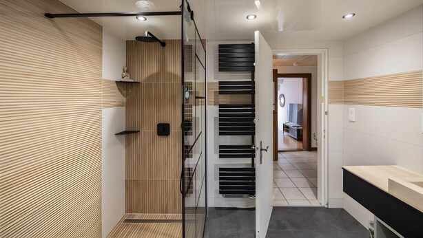 Une salle de bain moderne avec une douche, une porte en verre et un mur recouvert de panneaux en bois.