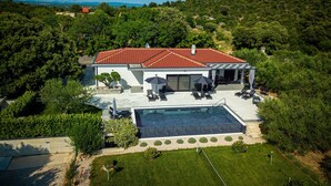 A modern house with a swimming pool, surrounded by lush greenery and a view of wind turbines in the distance. - Villa Danijela Zadarvillas (Polaca)