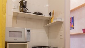 A compact kitchen with a gas stove, oven, microwave, and a small cabinet with kitchen utensils. - Ocean and Sugarloaf Mountain View Prf805 (Rio de Janeiro)