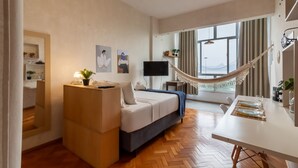 A modern hotel room with a bed, a desk, a hammock, and a large window. - Ocean and Sugarloaf Mountain View Prf805 (Rio de Janeiro)