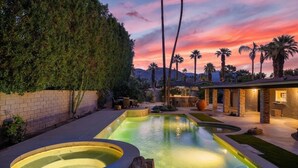 A pool area with a hot tub, surrounded by palm trees and a brick wall. - Remodeled Palm Desert Home by El Paseo: Mountain views, pool&spa, outdoor kitchen, sleeps 8 (Palm Desert)